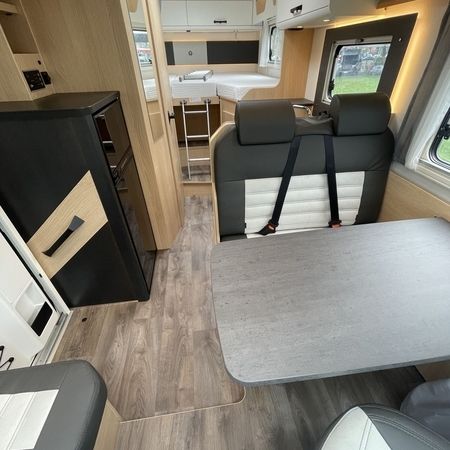 Innenraum eines Wohnmobils mit kompakter Küche und gemütlichem Essbereich mit Sitzgelegenheiten