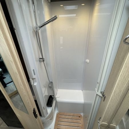 Eine Dusche mit Holzboden und modernem Duschkopf