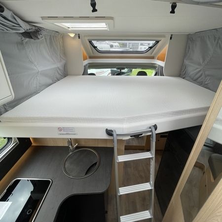 Innenraum eines Wohnmobils mit einem gemütlichen Bett und einem kompakten Waschbecken