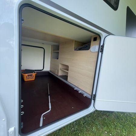 Ein teilweise offenes Staufach in einem Wohnmobil mit Holzregalen