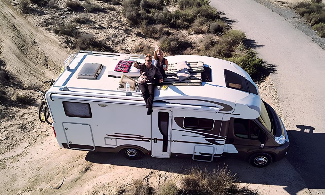 Ein Paar entspannt sich auf dem Dach ihres Wohnmobils, das auf einer unbefestigten Straße geparkt ist